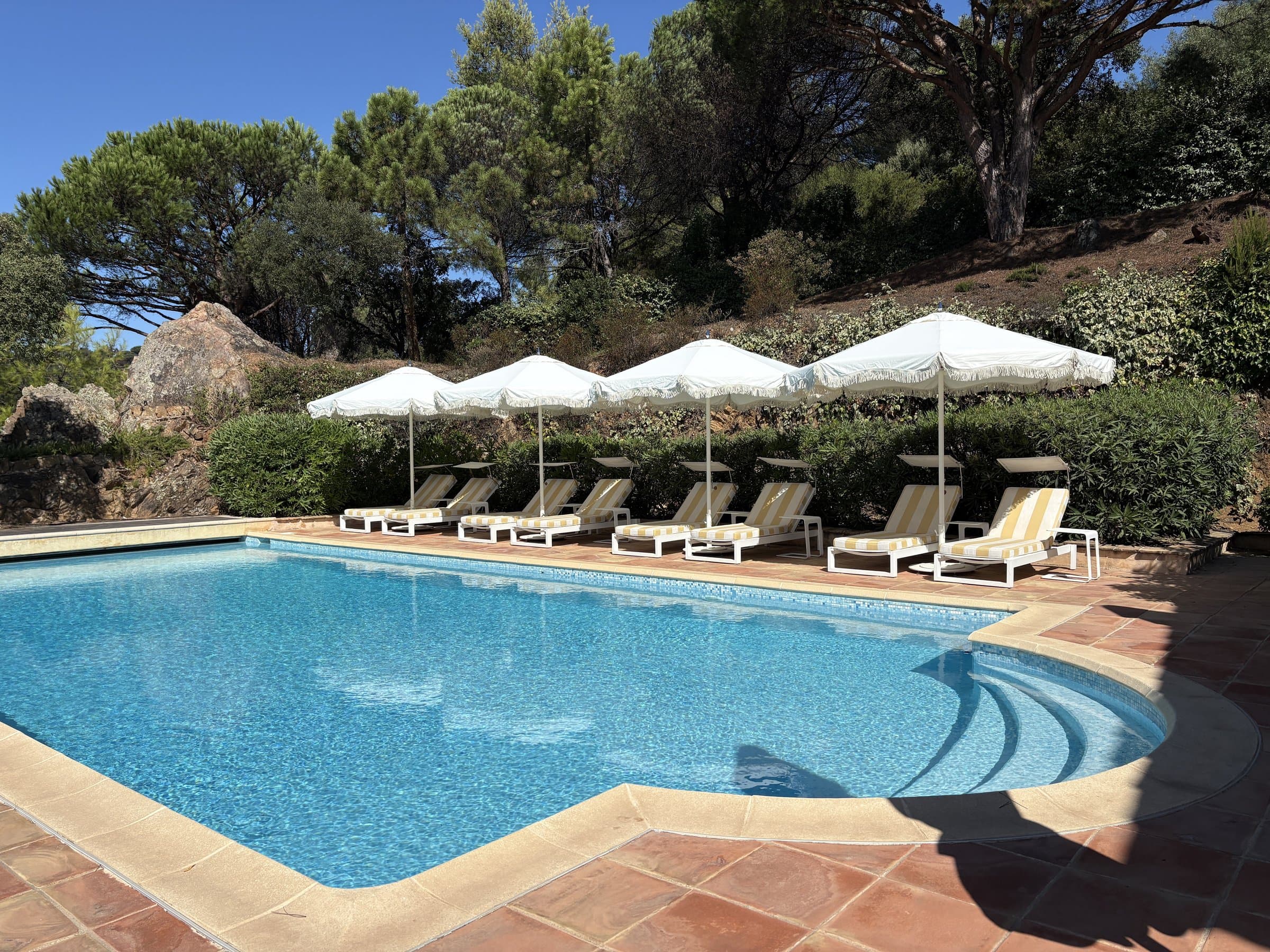 Private heated saltwater pool with striped loungers under white umbrellas, view 1 of 5.